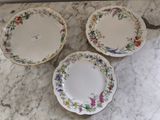 trois assiettes ornées de motifs floraux, posées sur un plan de travail en marbre