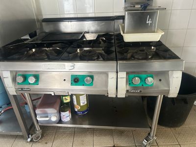 deux cuisinières dans une cuisine, avec une poubelle en arrière-plan