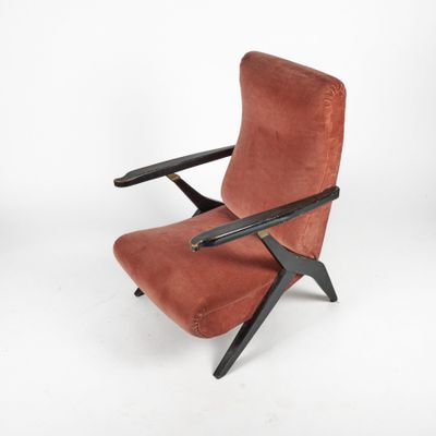 a red velvet lounge chair with black legs and a wooden frame