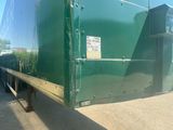 a green semi trailer parked on the side of the road