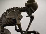 a bronze statue of a skeleton holding a ball