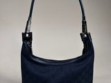a hand holding a blue purse with a black handle