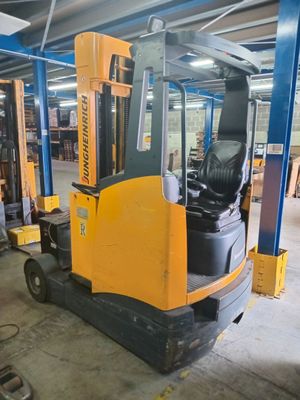 a forklift in a warehouse with other equipment in the background