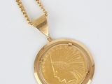 a gold coin pendant with a chain on a white surface
