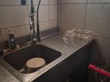 a sink with a faucet and a shopping cart in the corner