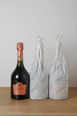 two bottles of champagne sitting on top of a wooden table next to a bottle of wine