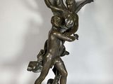 une statue antique en bronze représentant un ange tenant un enfant dans ses bras