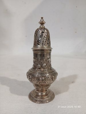 un petit objet argenté sur une surface blanche