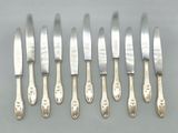 six silverplated knives and six knives on a table