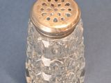a glass salt shaker with a gold top on a blue surface