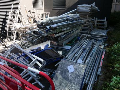 a pile of chairs and ladders outside of a building