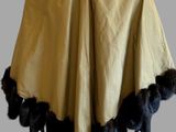 a mannequin wearing a yellow cape with black feathers