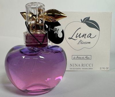 un flacon de parfum en verre violet orné d'une feuille d'or sur le bouchon, à côté d'une carte de visite