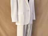 un costume blanc posé sur un mannequin, devant un fond beige