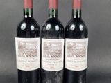 three bottles of red wine sitting on top of a table