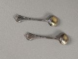 pair of silver spoons sitting on top of a white surface