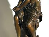 a bronze statue of a woman sitting on a rock