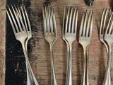 several forks and spoons are arranged on a table with silverware