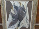tableau représentant un oiseau, encadré, posé sur un plancher en bois
