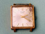a small square watch sitting on a blue surface