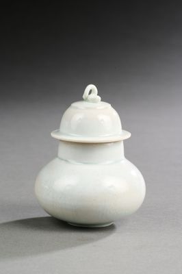 un vase blanc muni d'un couvercle, posé sur une table