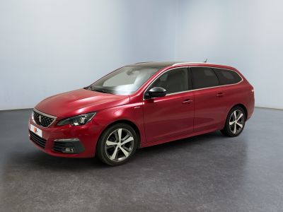 La voiture rouge est garée dans une pièce aux murs blancs.
