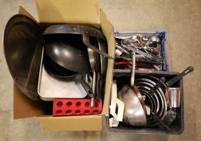 une boîte remplie d'ustensiles de cuisine et de casseroles posée par terre