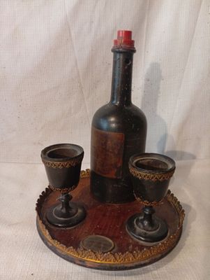 une bouteille et des tasses posées sur un plateau, sur fond blanc