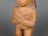 une vieille statue en bois représentant une personne tenant un bébé dans ses bras