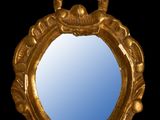 un miroir doré orné d'un oiseau sur fond noir