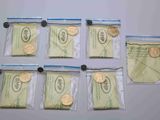 cinq sachets de pièces et un sachet de billets sur la table