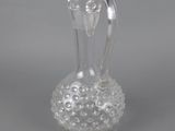 a clear glass vase on a gray surface with a handle