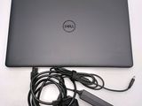 dell laptop with power cord and charger sitting on a white surface