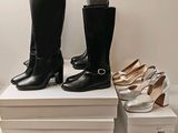deux paires de bottes à talons hauts noires et blanches posées sur une pile de cartons blancs