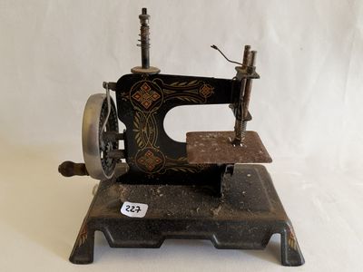 une machine à coudre noire et dorée posée sur une surface blanche