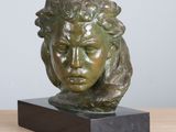 bronze sculpture of a woman ' s head on a wooden base