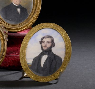 trois portraits miniatures d'un homme et d'une femme posés sur un coussin de velours rouge