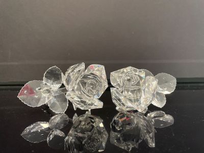 trois roses en cristal posées sur une surface noire