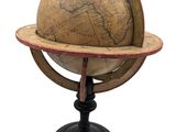 un vieux globe terrestre posé sur un socle, avec un fond blanc