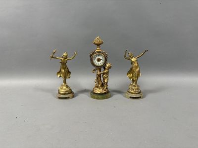 trois figurines dorées surmontées d'une horloge