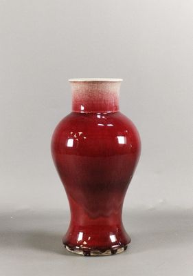 un vase rouge avec un couvercle blanc posé sur une table