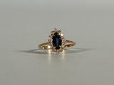 a close up of a blue sapphire and diamond ring on a white surface