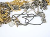 a pile of silver and gold chains on a white surface