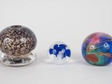 trois boules de verre de couleurs différentes posées les unes à côté des autres sur une surface blanche