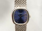 a silver watch with a blue face sitting on a table