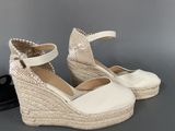 pair of women ' s white wedged sandals on a gray surface