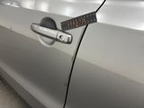 the door handle of a silver car with a sticker on it