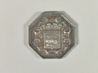 une pièce d'argent sur laquelle est représenté un blason