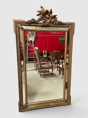 une image représentant un miroir avec un cadre doré et un mur rouge en arrière-plan
