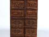 two old books are stacked on top of each other on a white surface